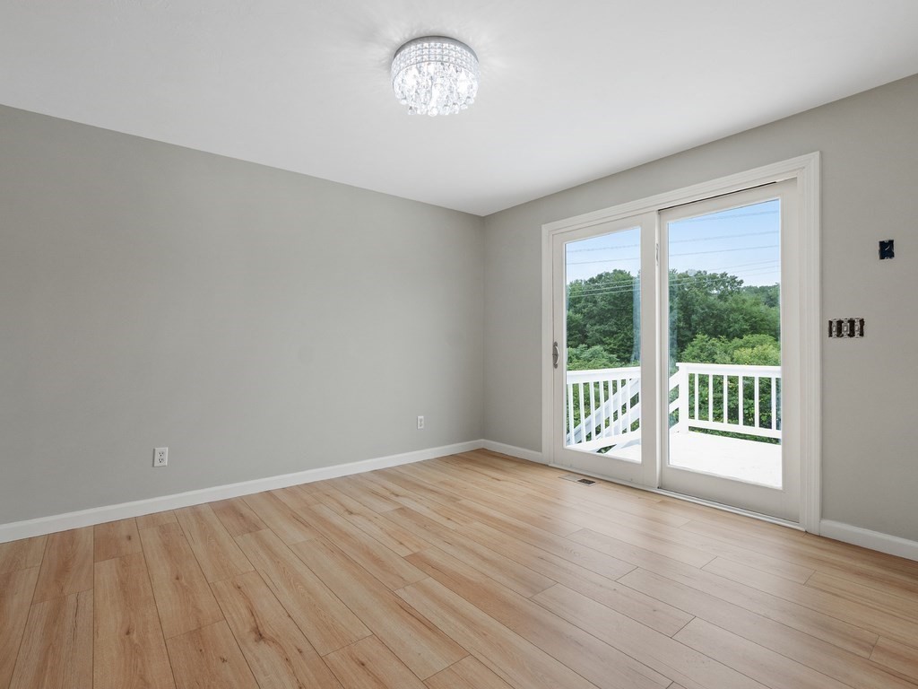 Empty room with light plank flooring and a sliding glass door to a deck.