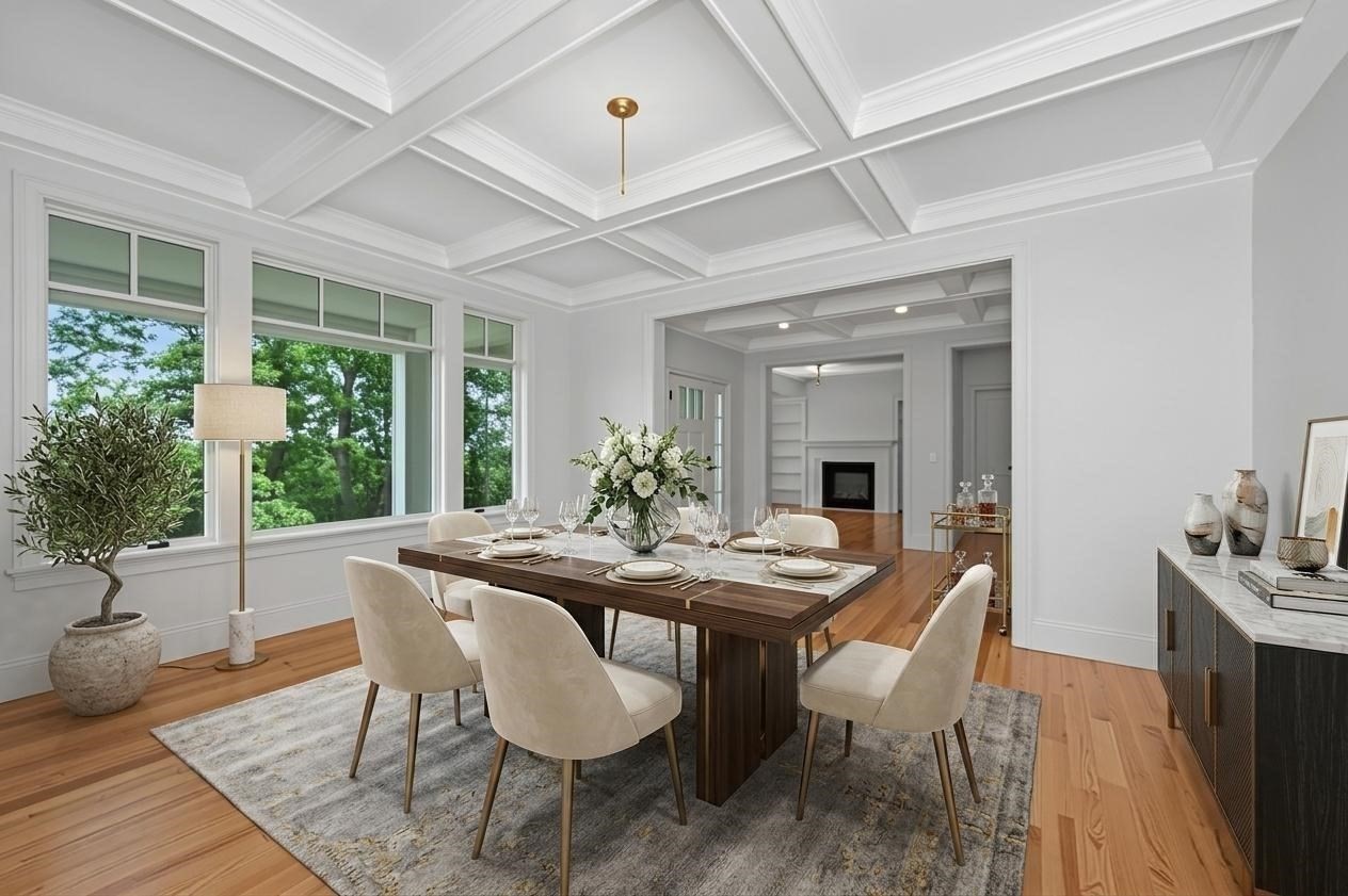 Staged dining room with a coffered ceiling, large windows, and a set dark wood table.