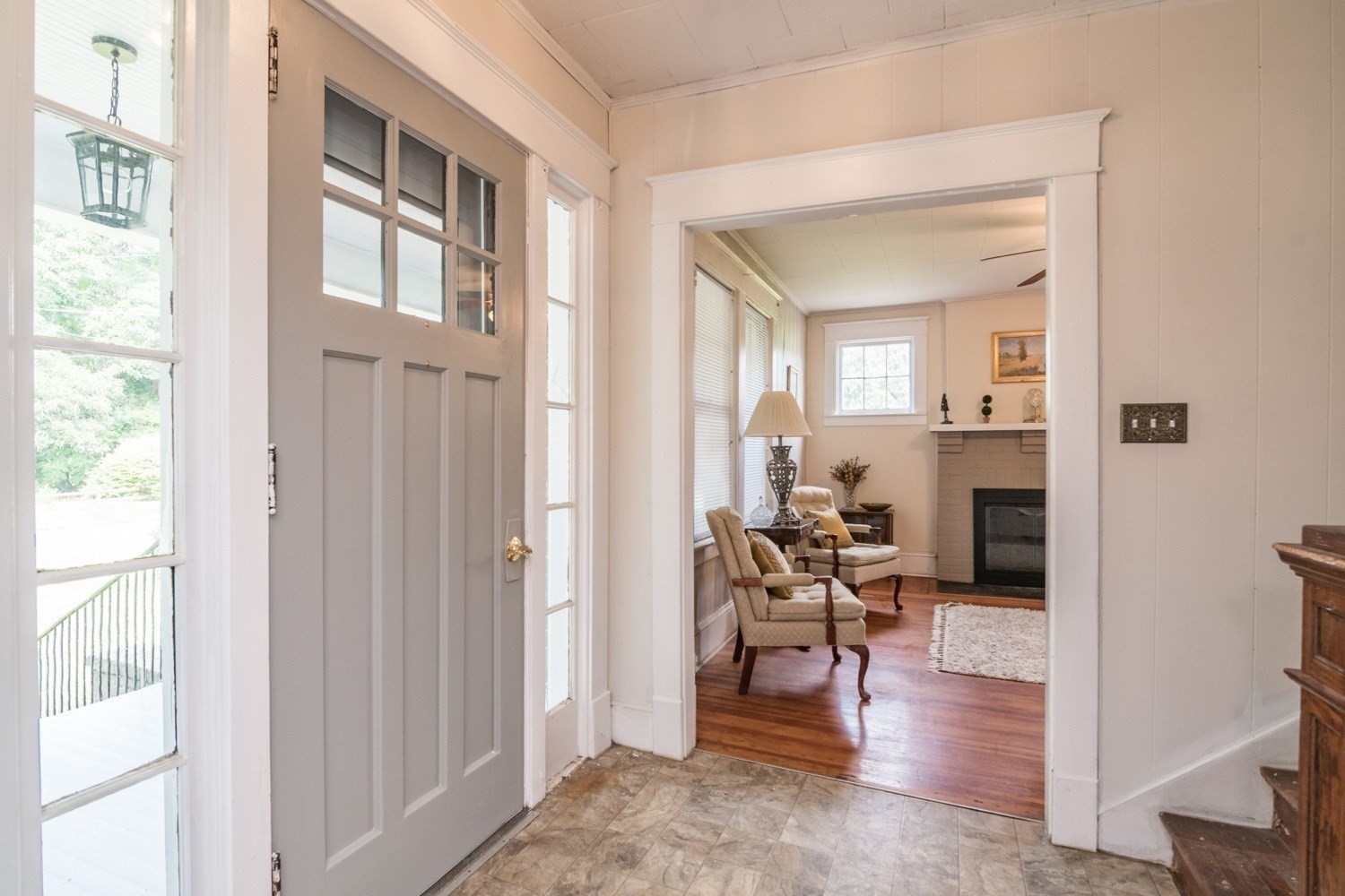 Entry hall opening to a furnished living room with a fireplace and hardwood floors.