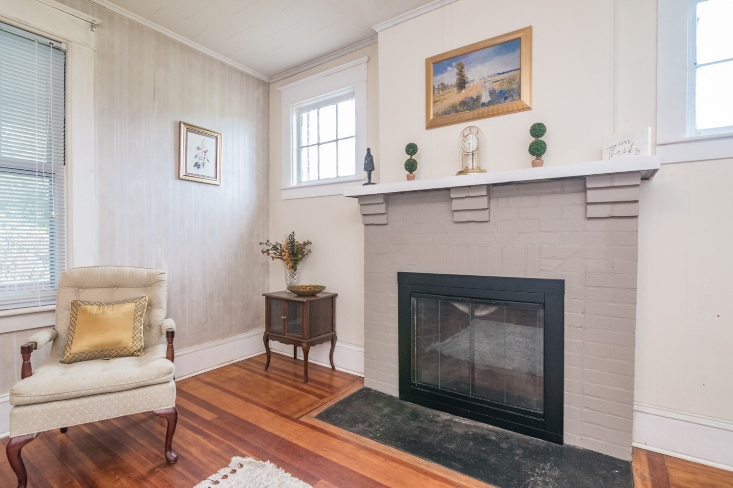 Living room with a white brick fireplace, dark firebox, and polished hardwood floors.