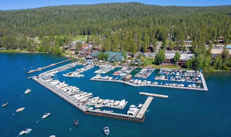 Aerial view of a lakeside marina with boats docked beneath a forested hillside.