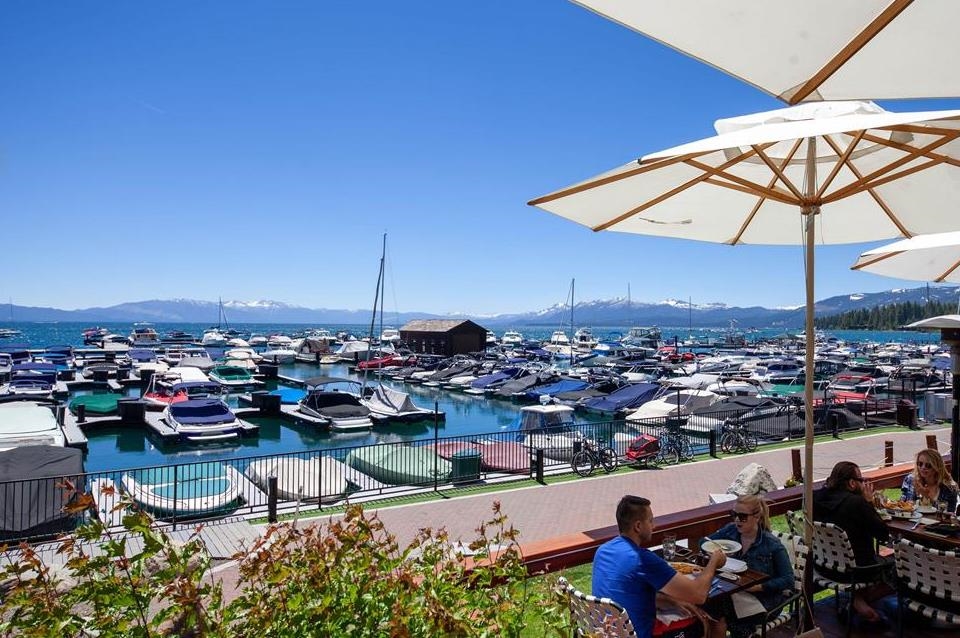 Lake Tahoe marina and snow-dusted mountains viewed from a shaded restaurant patio.