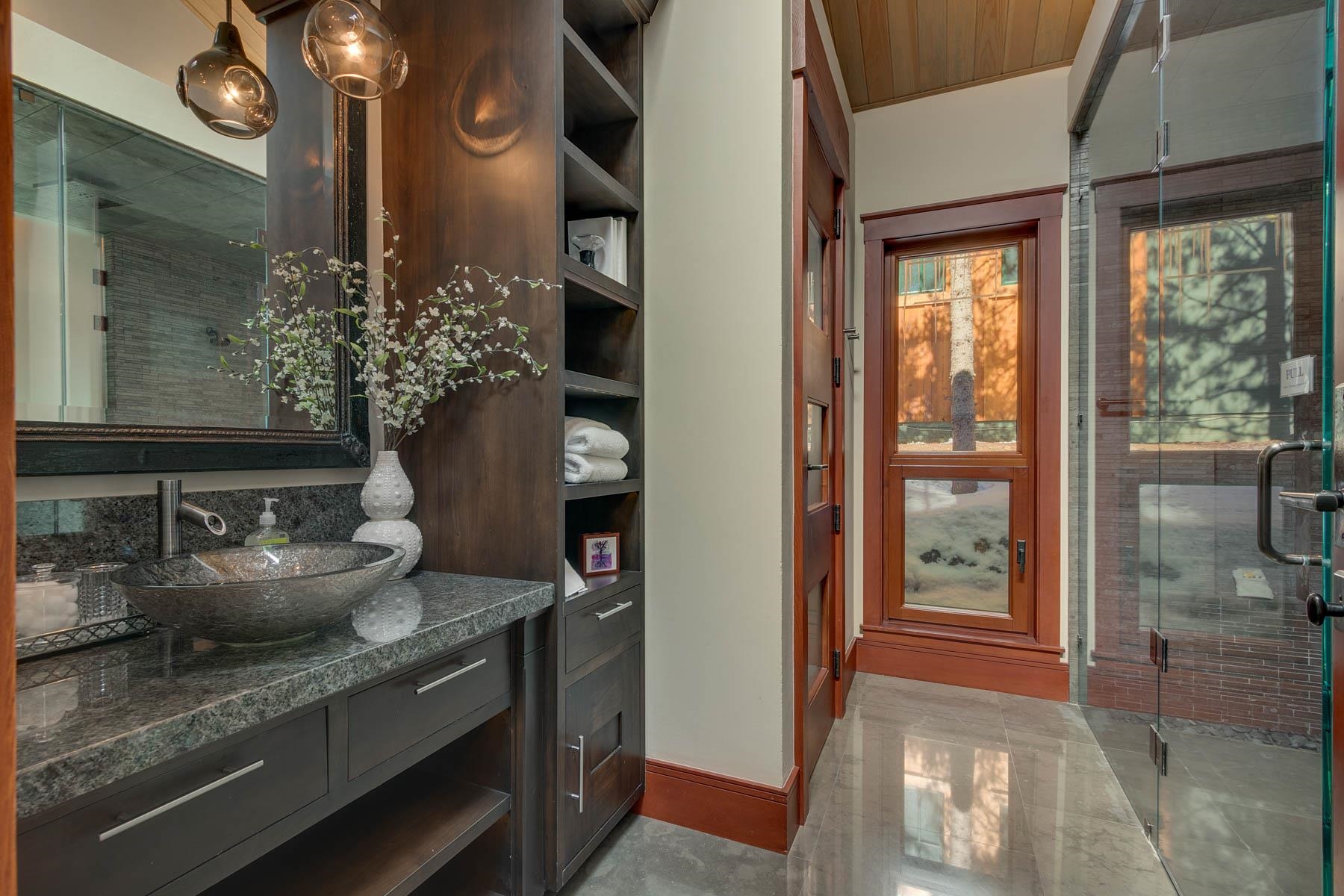 Bathroom with a granite vanity and vessel sink beside a glass-enclosed shower.