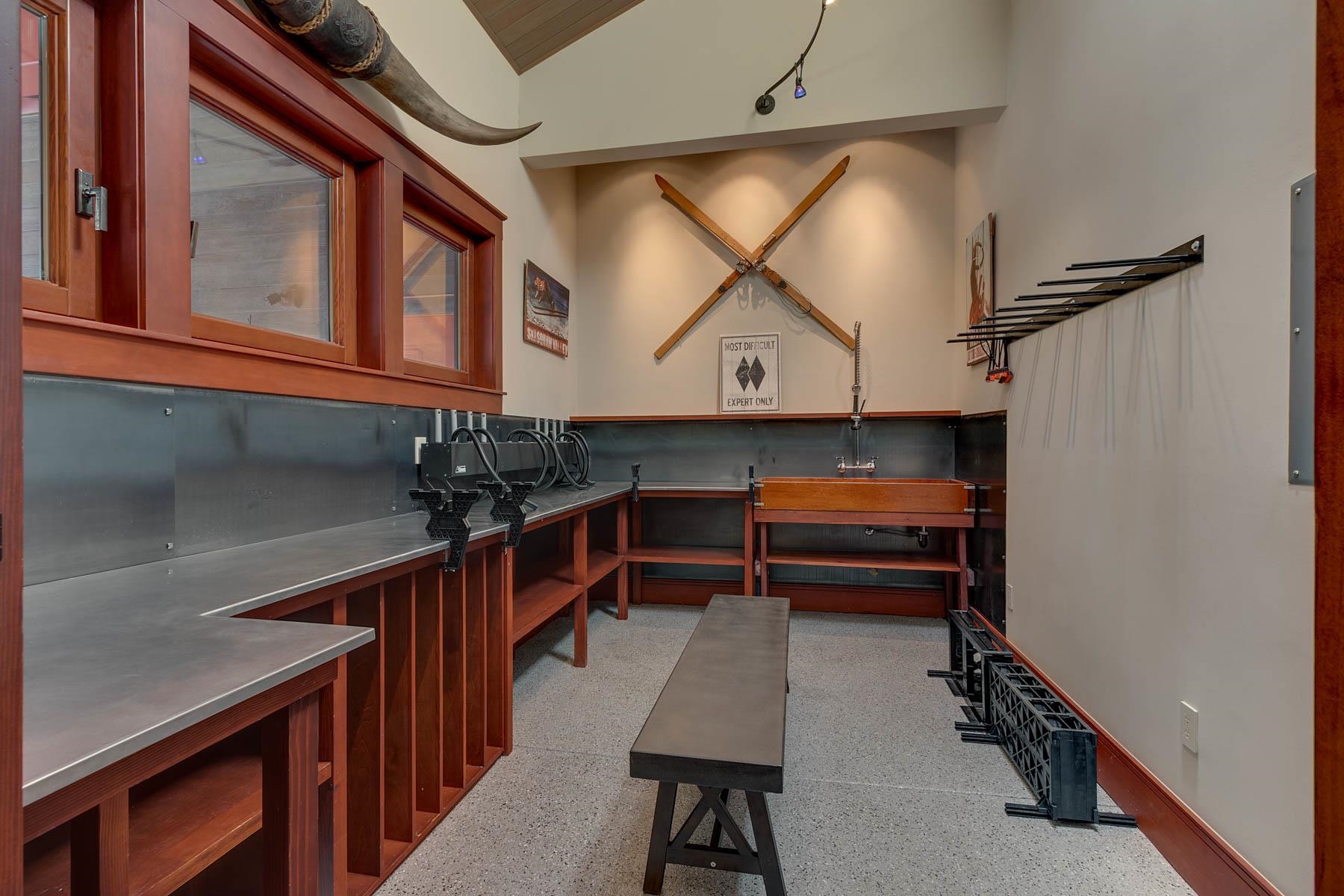 Ski tuning room with long workbenches, wall-mounted crossed skis, and racks for ski equipment.