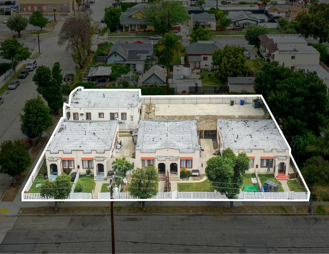 Aerial view of a white-roofed multifamily property outlined in white, with fenced courtyards.