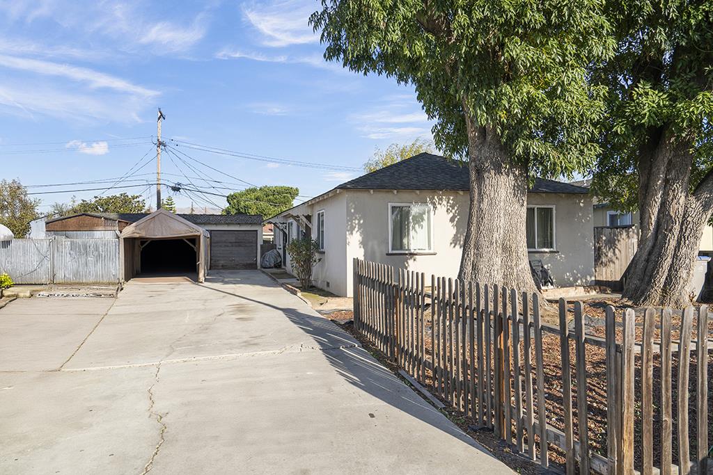 Single-story home with a wide driveway, carport, garage, and large shade trees.