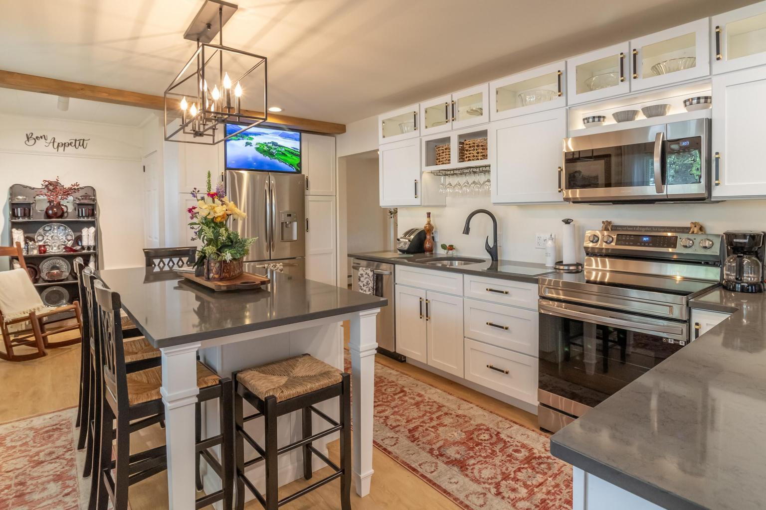 Kitchen with white cabinetry, stainless steel appliances, and a large island with bar seating.
