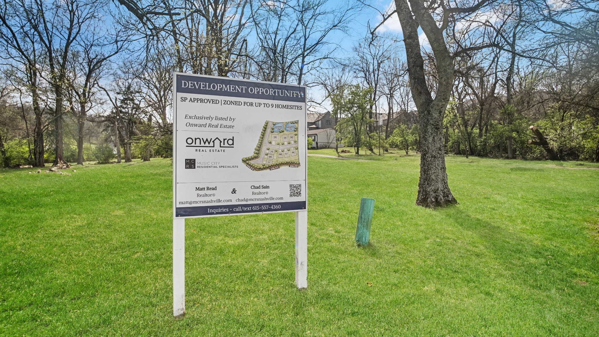 Grassy development parcel with a sign advertising zoning for up to nine homesites.