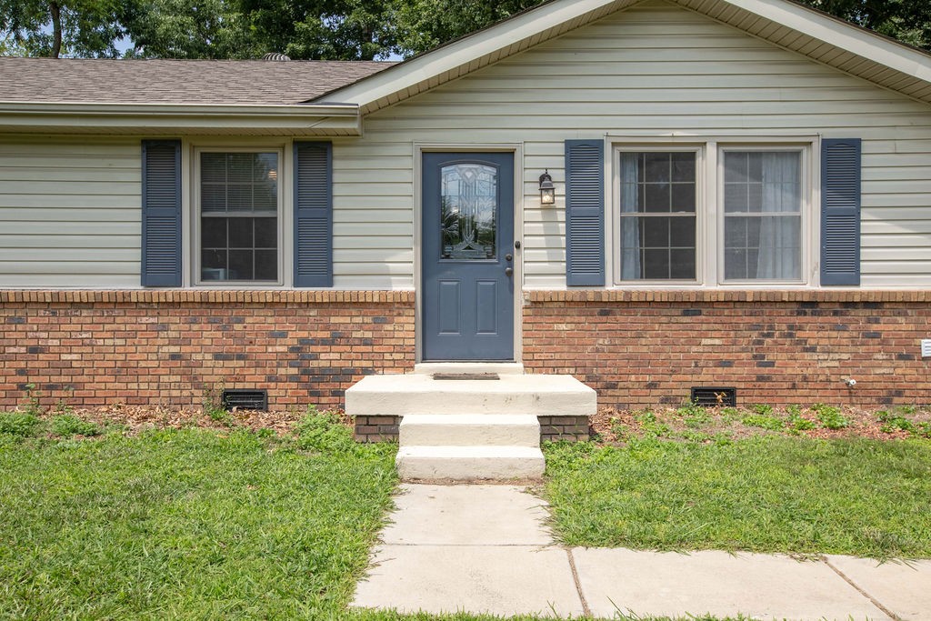 Single-story home with a blue front door, brick lower facade, and concrete entry steps.