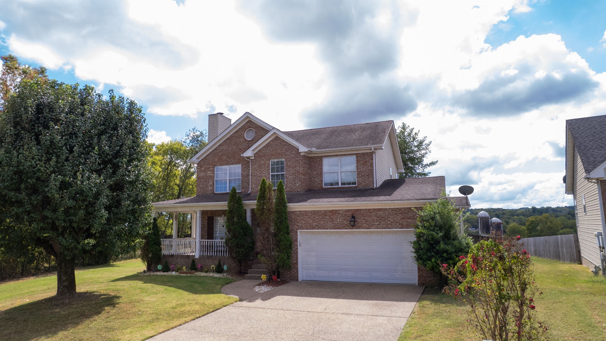 Two-story brick house with a covered porch, double garage, and wide driveway.