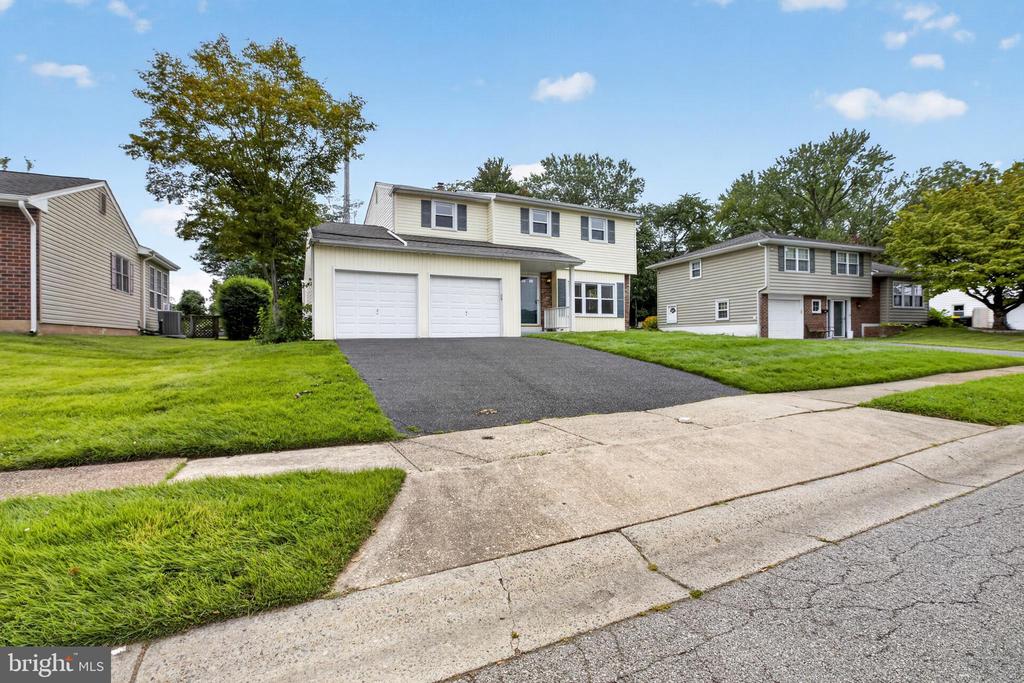 Two-story house with a double garage, wide driveway, and green front lawn.