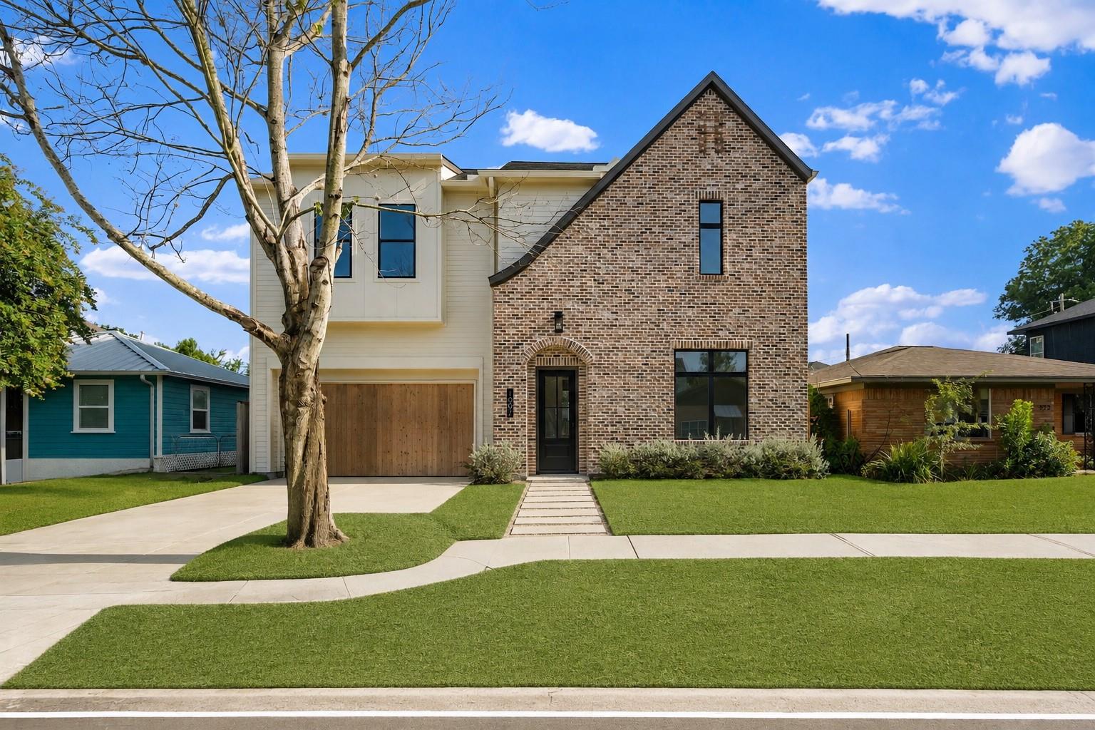 Modern two-story brick and white-sided house with a wood garage door and front lawn.