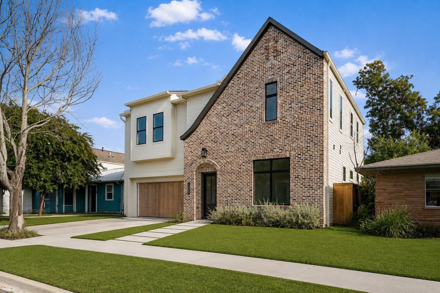 Two-story home with a brick gable facade, white siding, and wood garage door.