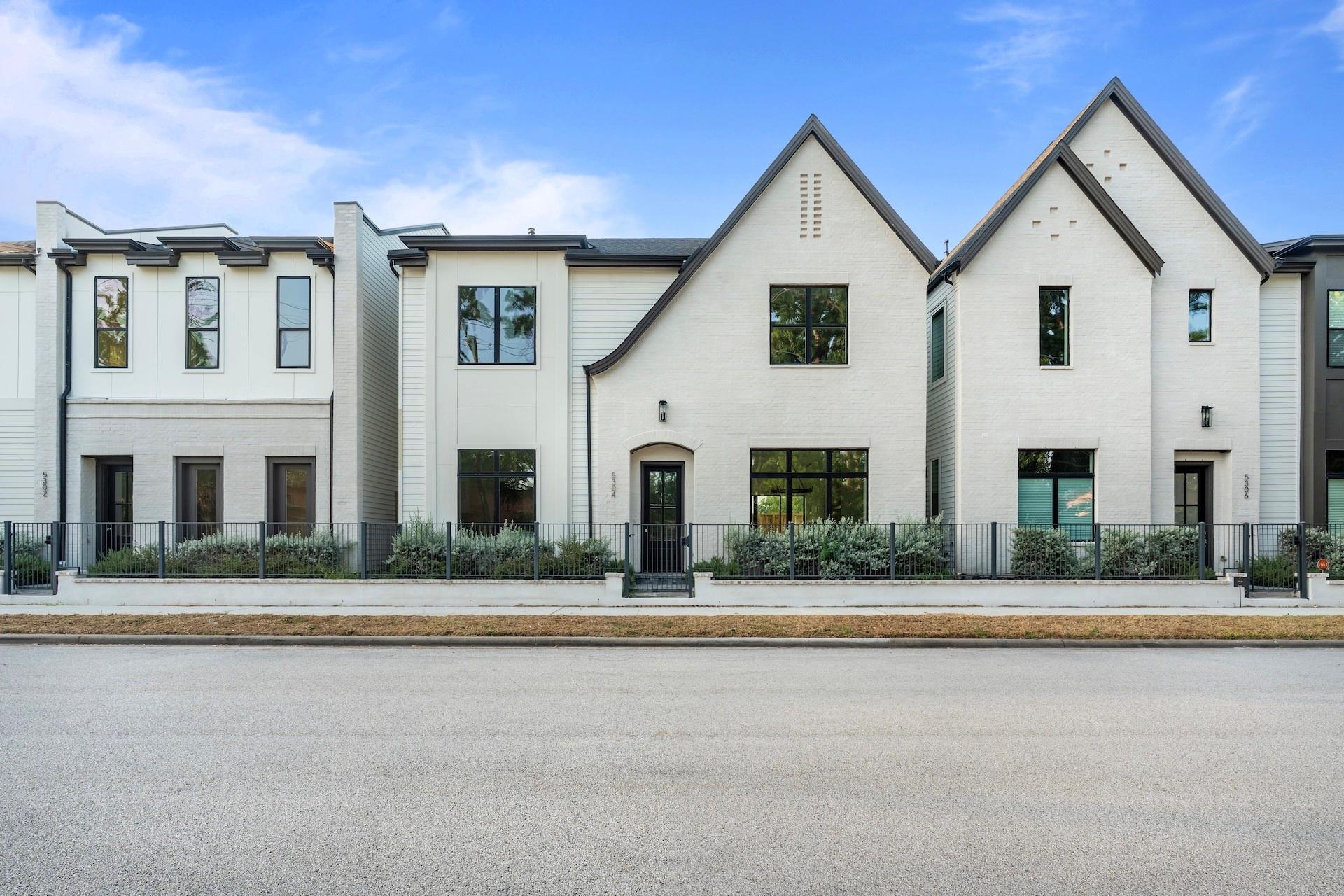 White-brick attached townhomes with steep gables and fenced front gardens.
