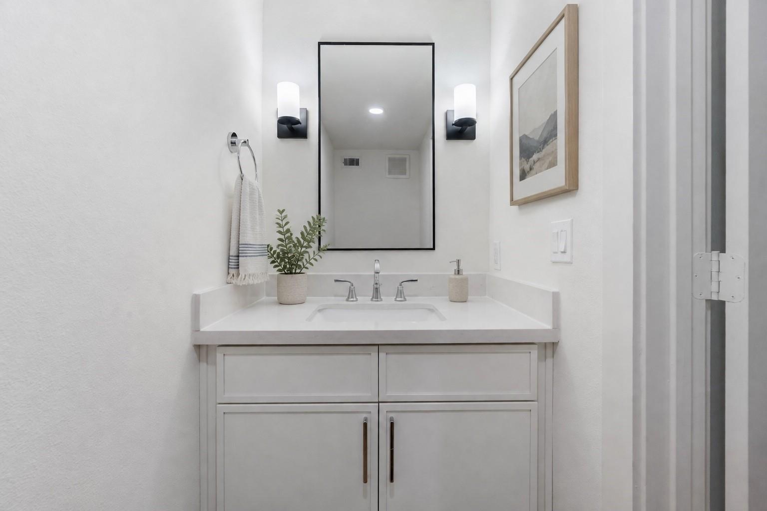 Bathroom vanity with a pale countertop, chrome fixtures, and a large black-framed mirror.