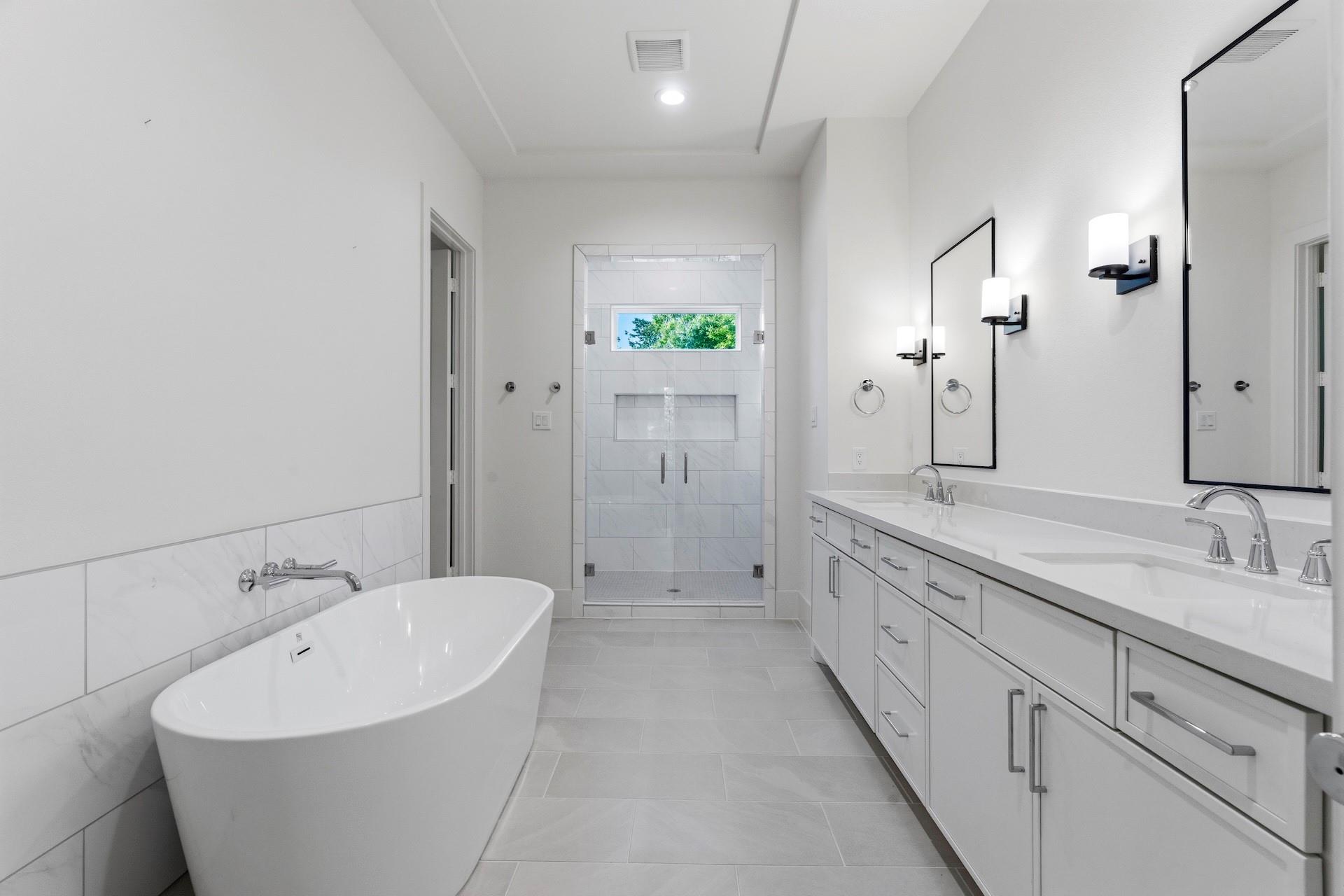 Modern bathroom with a freestanding tub, glass shower, and long double vanity.
