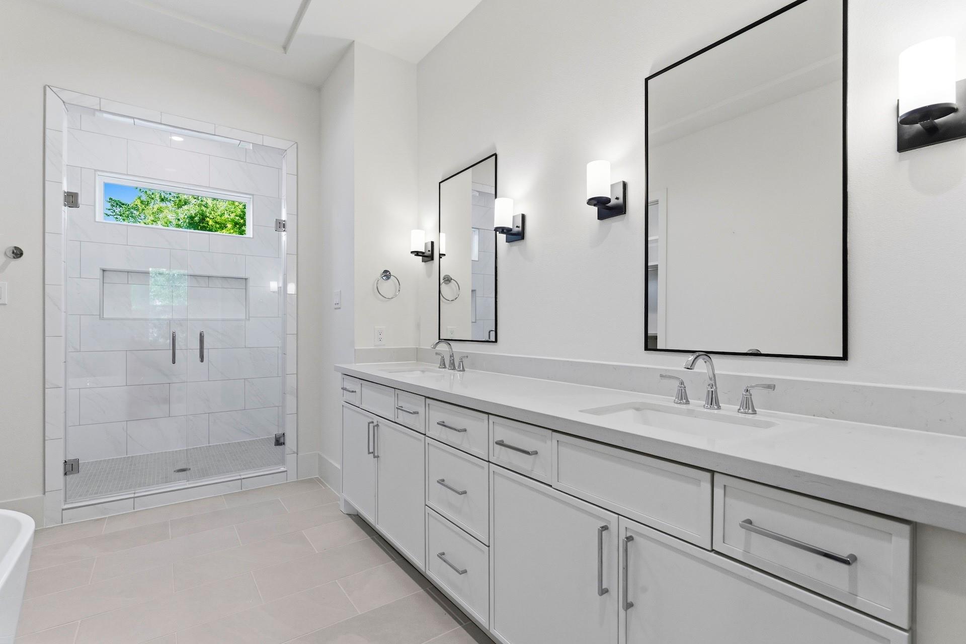 Bathroom with a double-sink vanity and a glass-enclosed tiled shower.