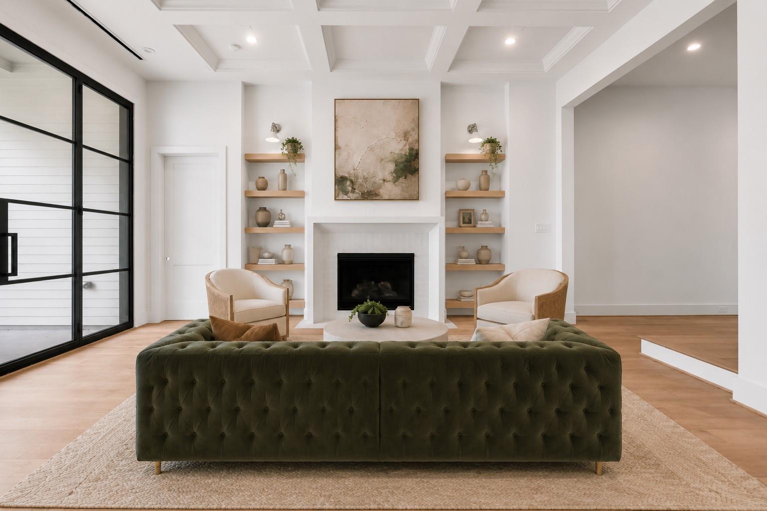 Staged living room with a white fireplace, built-in shelves, and deep green tufted sofa.