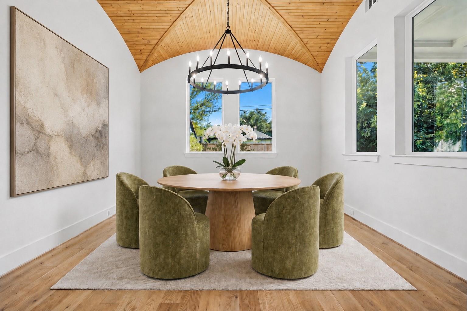 Dining room with a round wood table, olive-green chairs, and a vaulted wood ceiling.