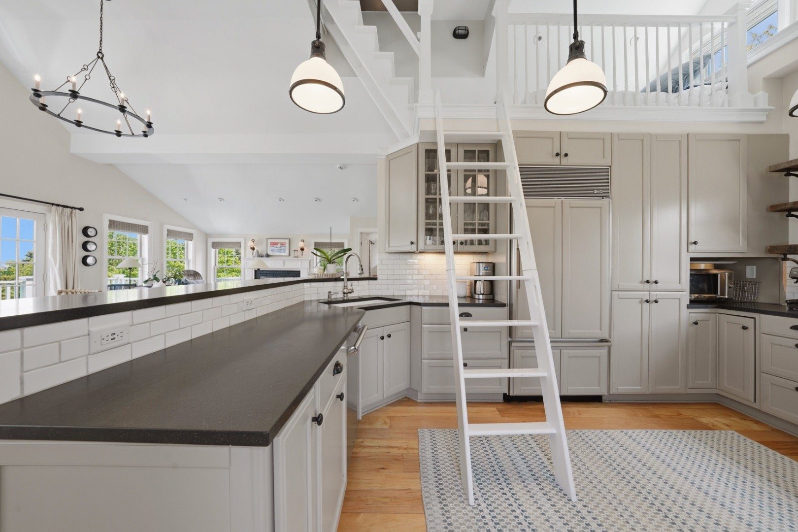 Kitchen with white cabinets, dark countertops, and a ladder to an upper loft.