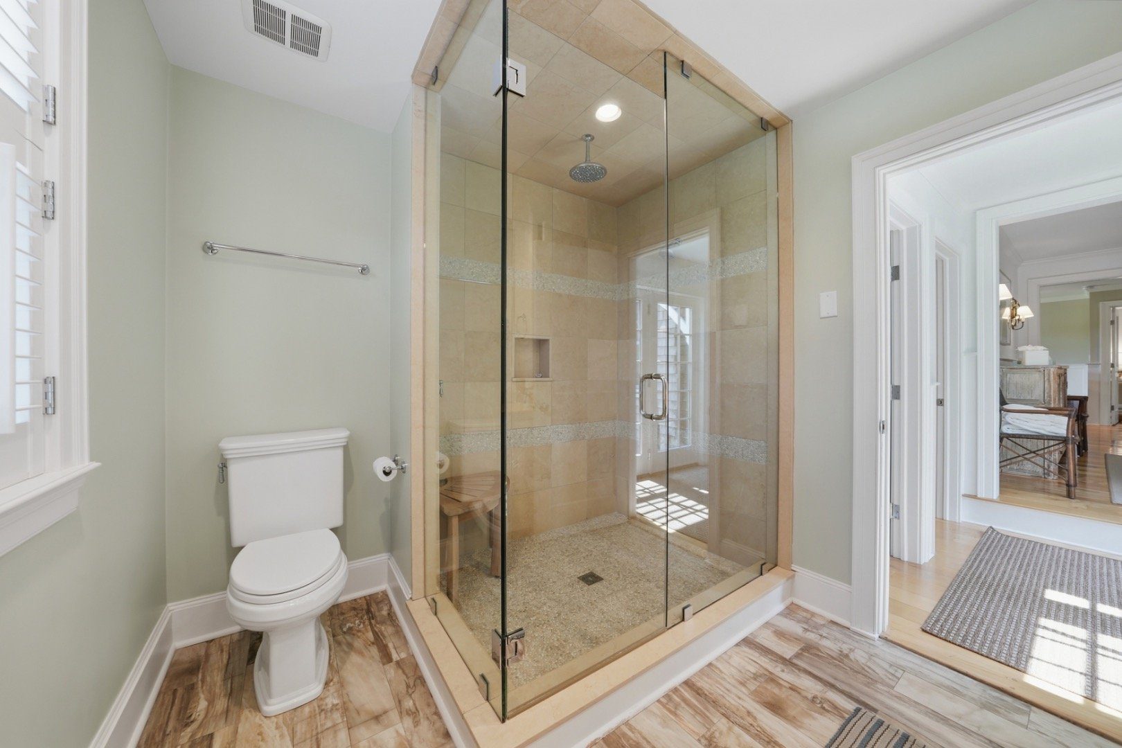 Bathroom with a glass-enclosed tiled walk-in shower and toilet.