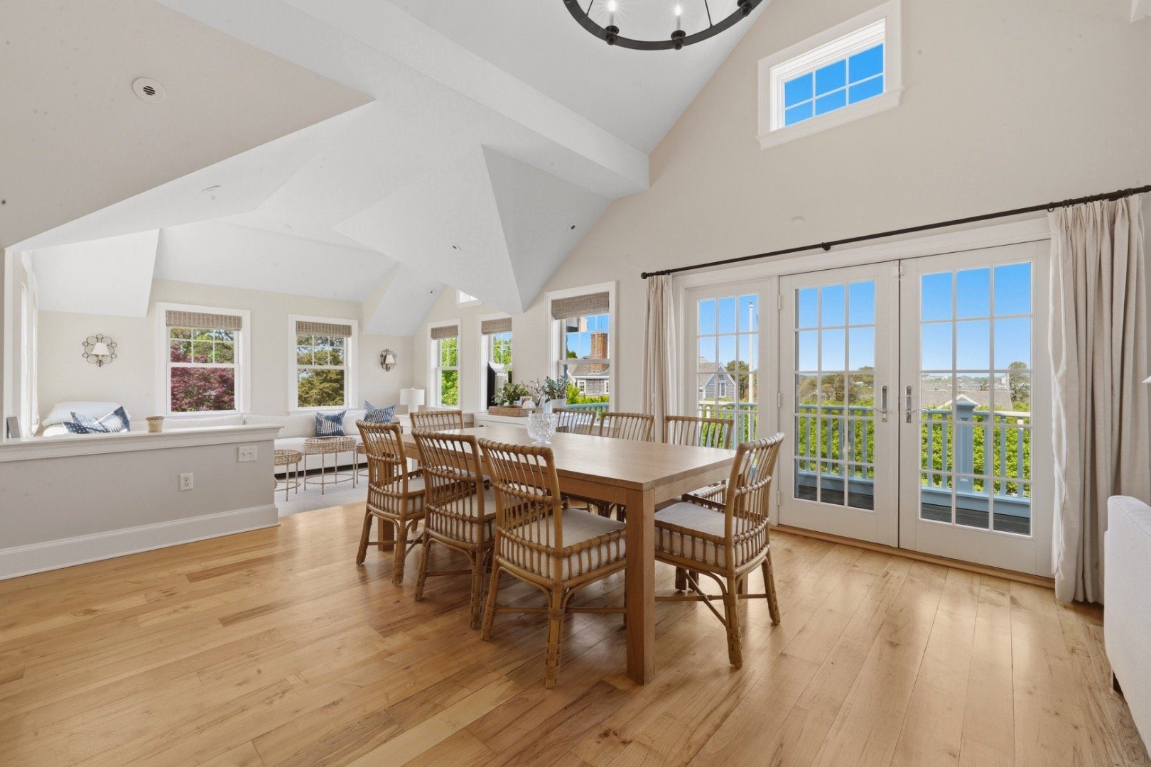 Furnished dining room with a vaulted ceiling, hardwood floors, and French doors opening to a deck.