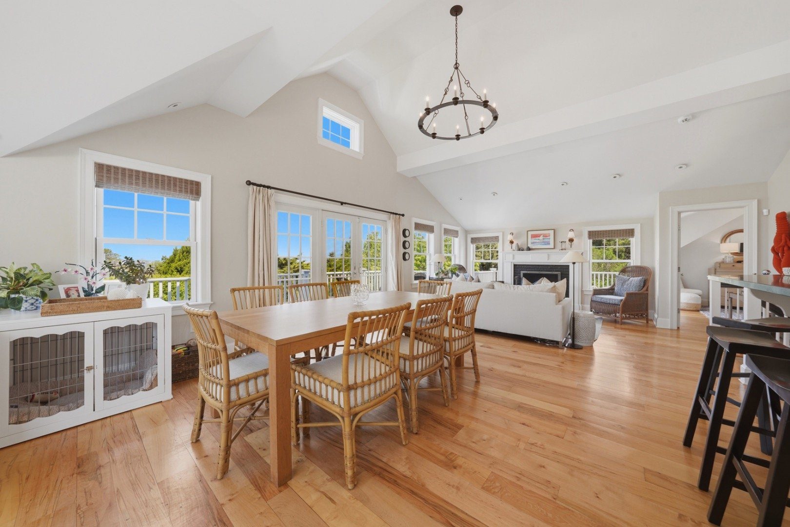 Open-plan dining and living room with vaulted ceilings, wood floors, and French doors.
