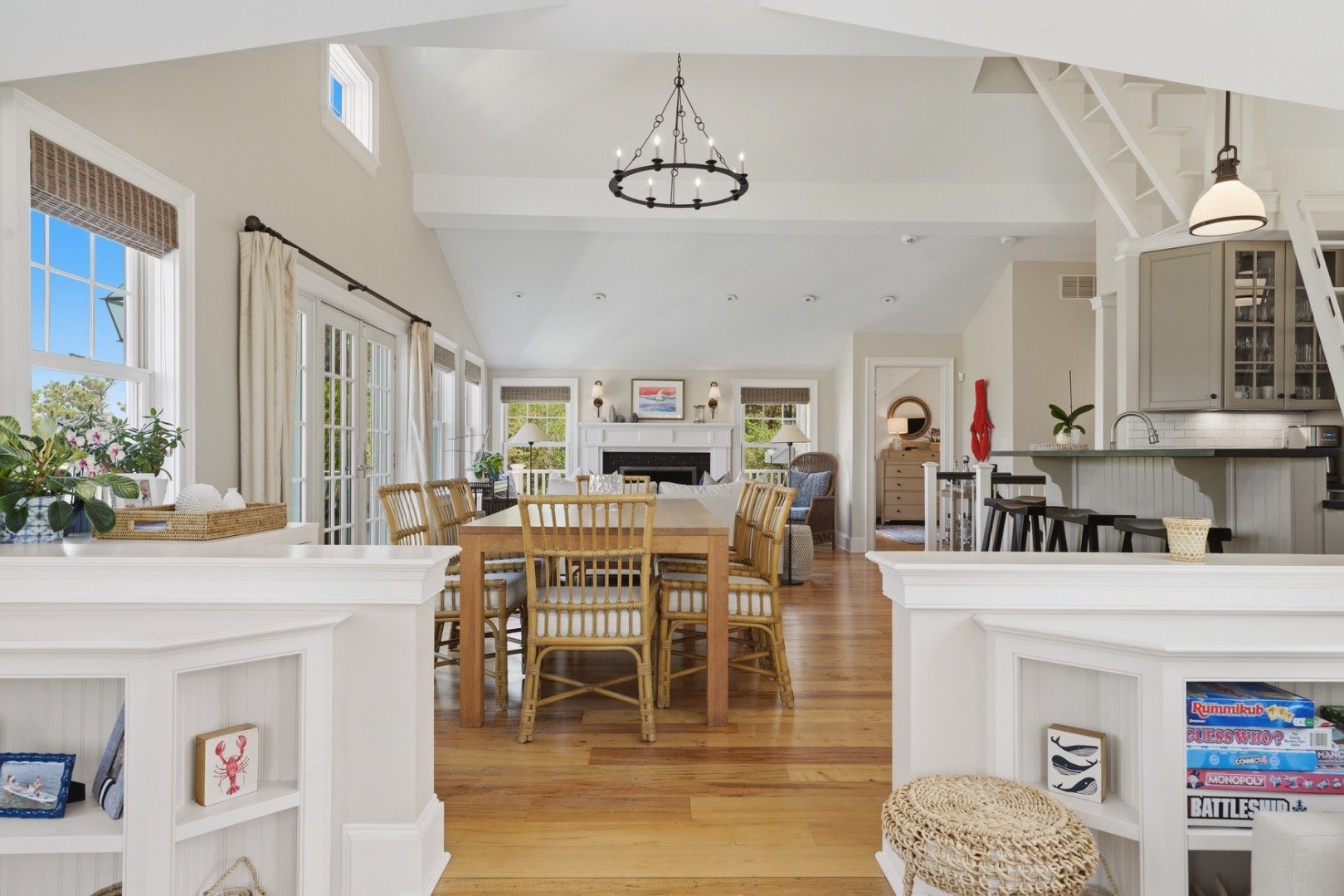 Open-plan dining and living room with a long wooden table, fireplace, and adjoining kitchen.