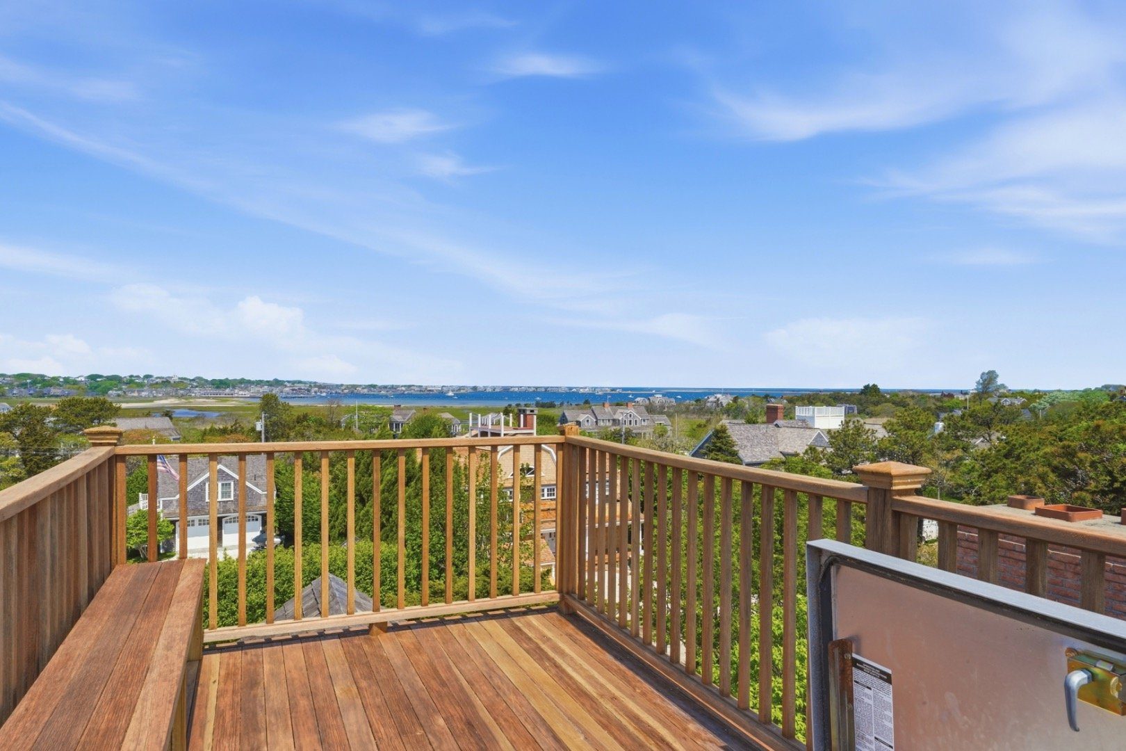 Rooftop deck overlooking Nantucket harbor, with wooden railings and a built-in bench.