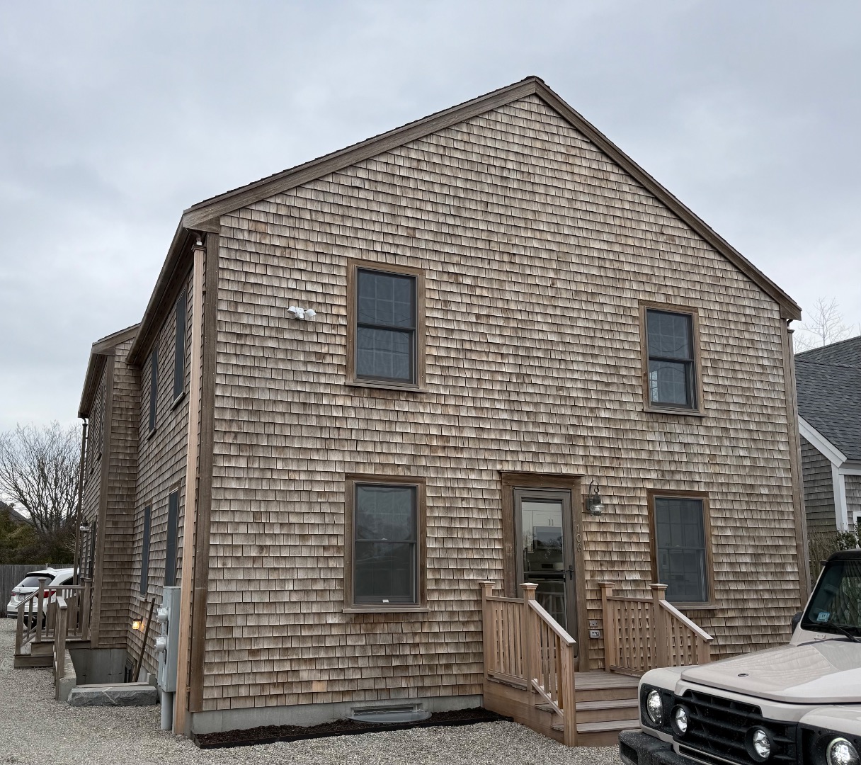 Two-story shingle-sided home with a small front porch and wooden entry steps.