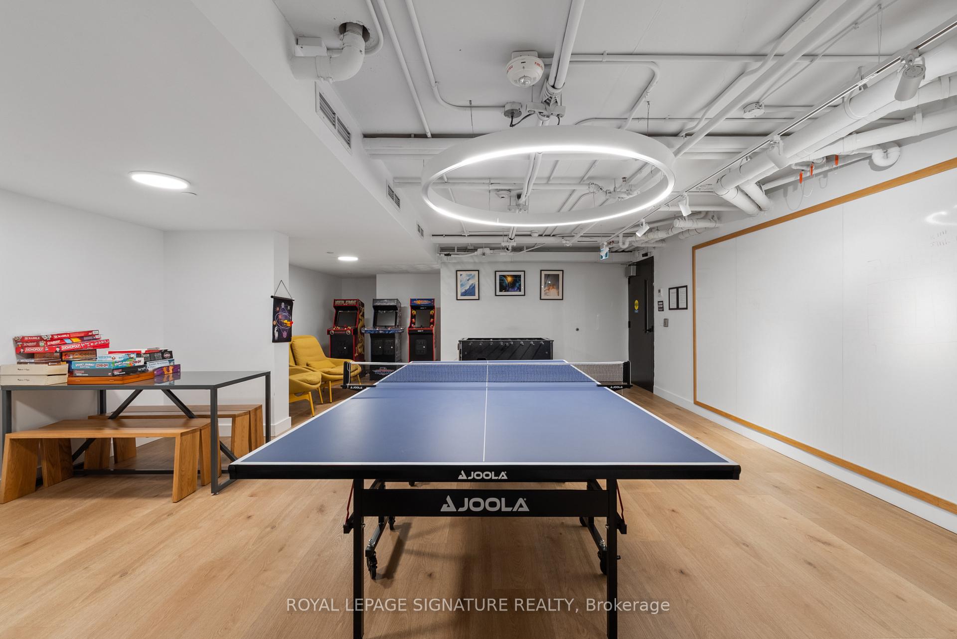 Condominium recreation room with a blue ping-pong table, arcade games, and board games.