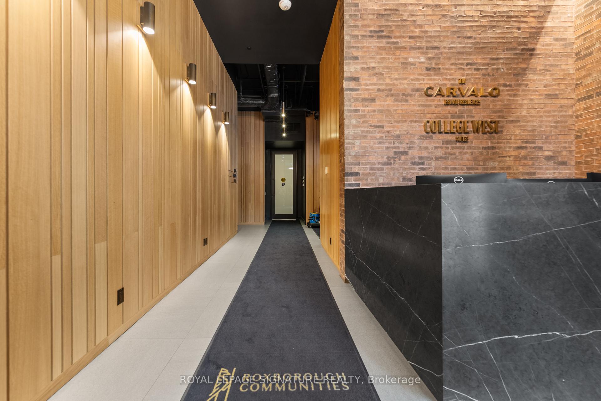Condominium lobby with a black stone reception desk and warm wood-paneled corridor.