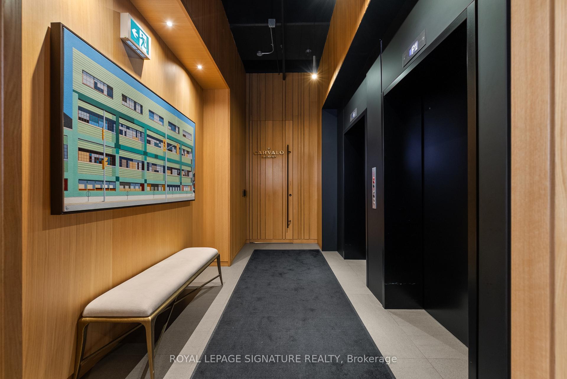 Condominium elevator lobby with wood paneling, framed artwork, and a long upholstered bench.