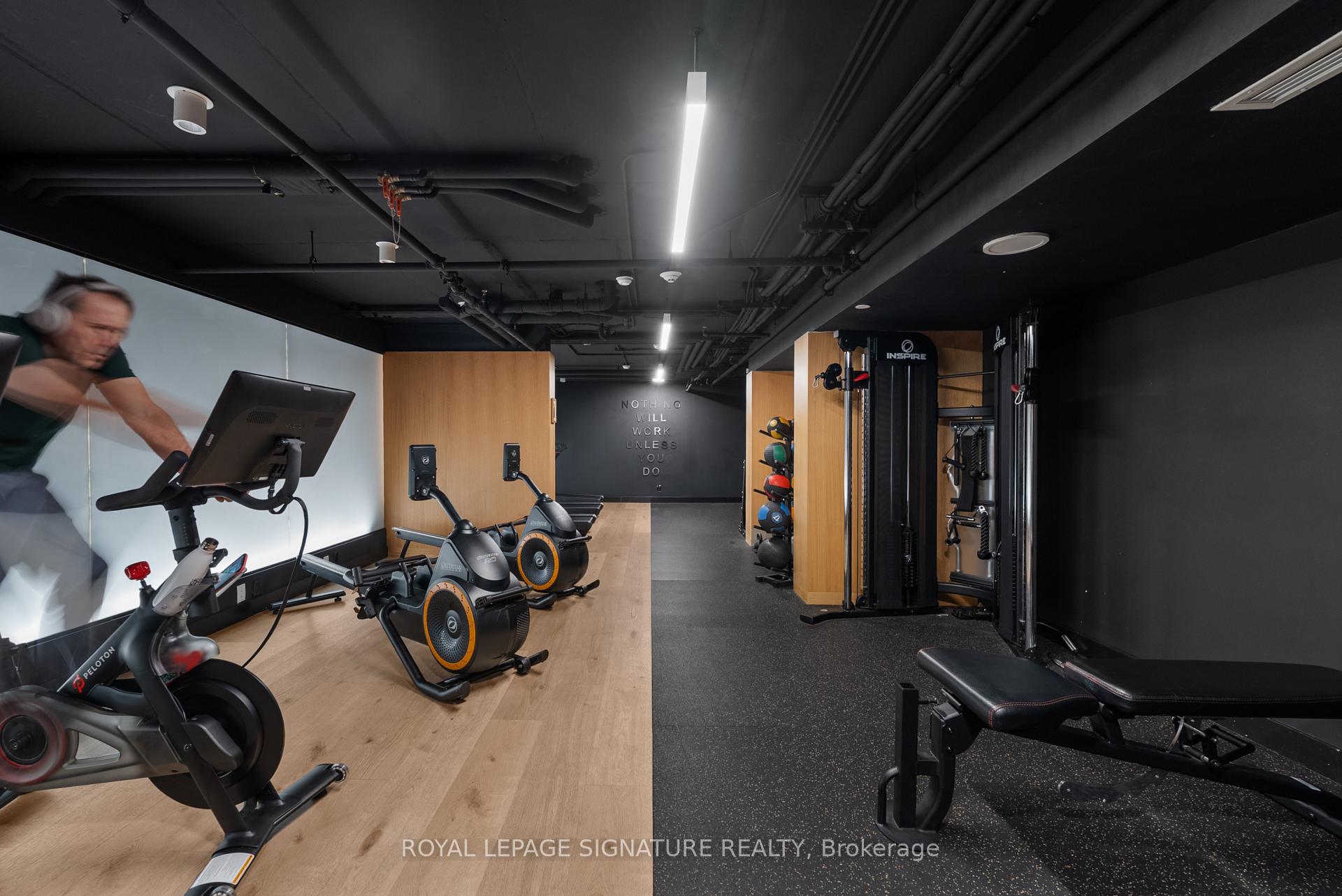 Condominium gym with Peloton bikes, weight-training machines, and a wood-and-rubber floor.