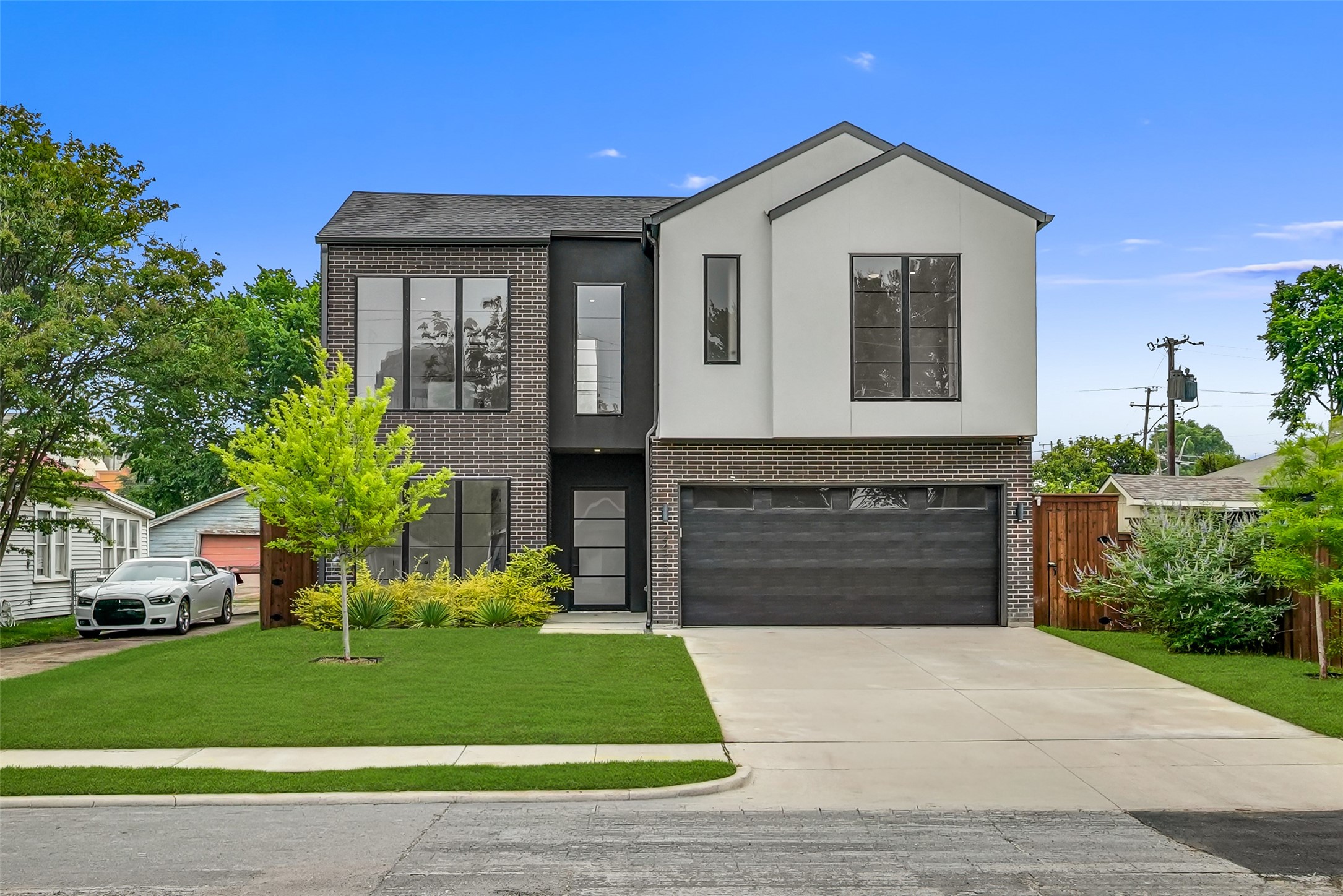 Modern two-story house with dark brick, white upper facade, and a wide garage.