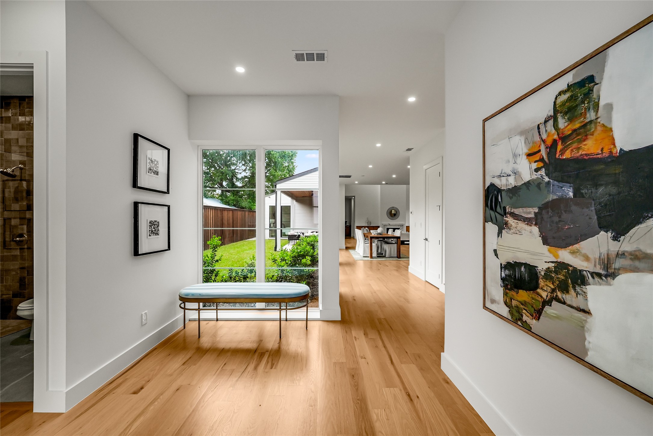 Entry hall with light wood floors, a window overlooking the yard, and a cushioned bench.