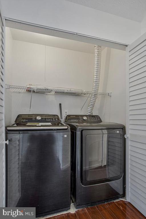 Laundry closet with front-loading washer and dryer beneath a wire storage shelf.