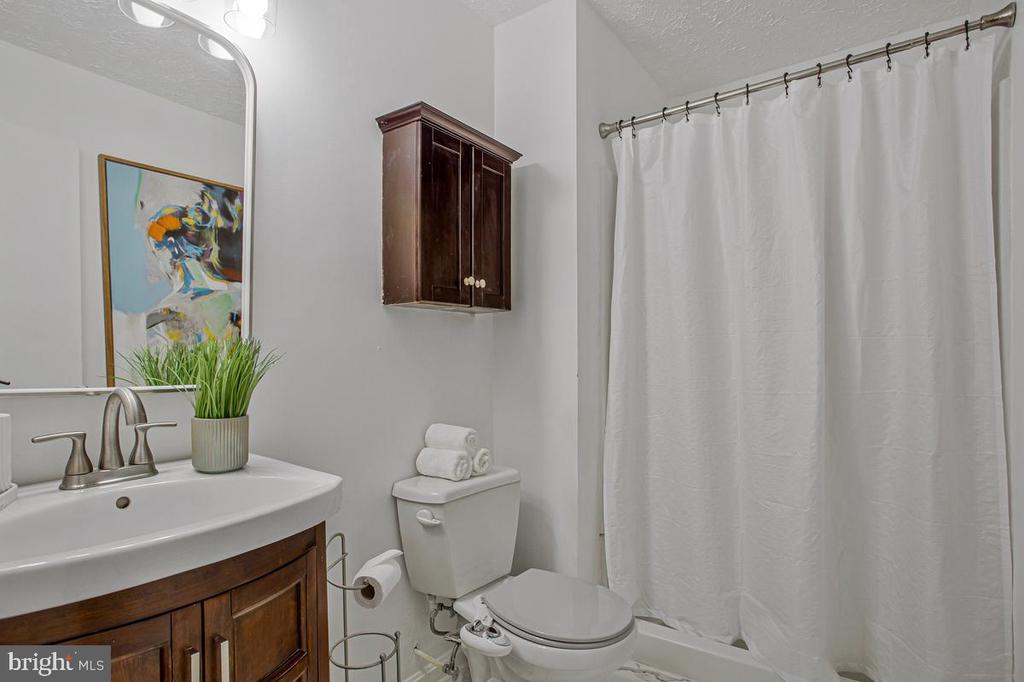 Bathroom with a dark wood vanity, white fixtures, and a white shower curtain.