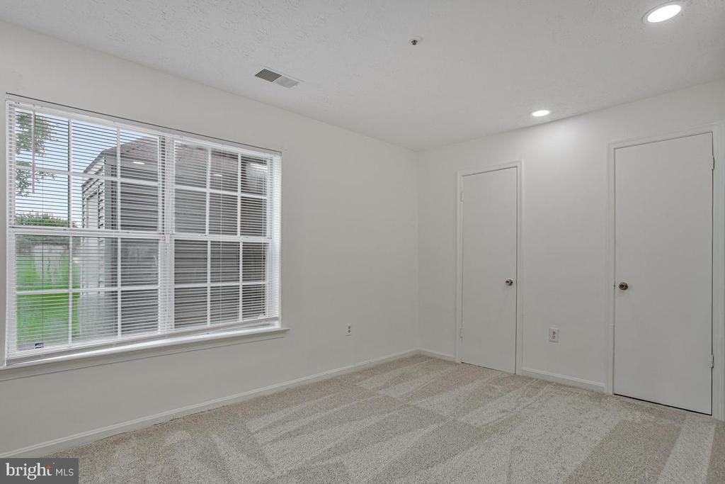 Empty carpeted bedroom with a large window and two doors.