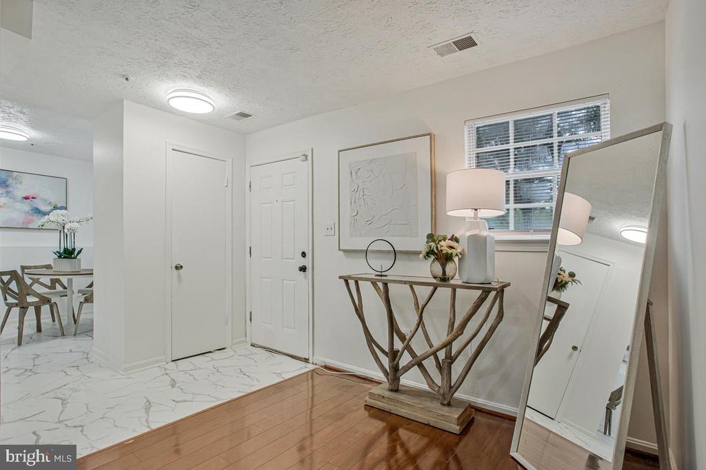 Entryway with a wood console table, flowers, and large leaning mirror beside the front door.