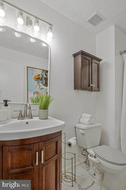 Bathroom with a dark wood vanity, illuminated mirror, and matching wall cabinet.