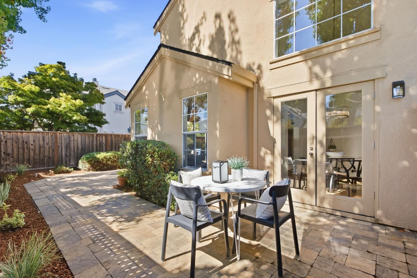 Rear patio with paved terrace, outdoor dining set, and glass doors to the home.