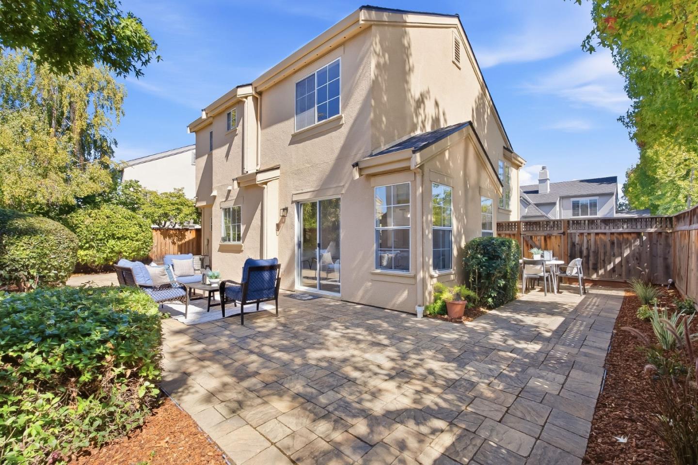 Backyard patio with a broad stone-paver terrace, outdoor seating, and a fenced garden.