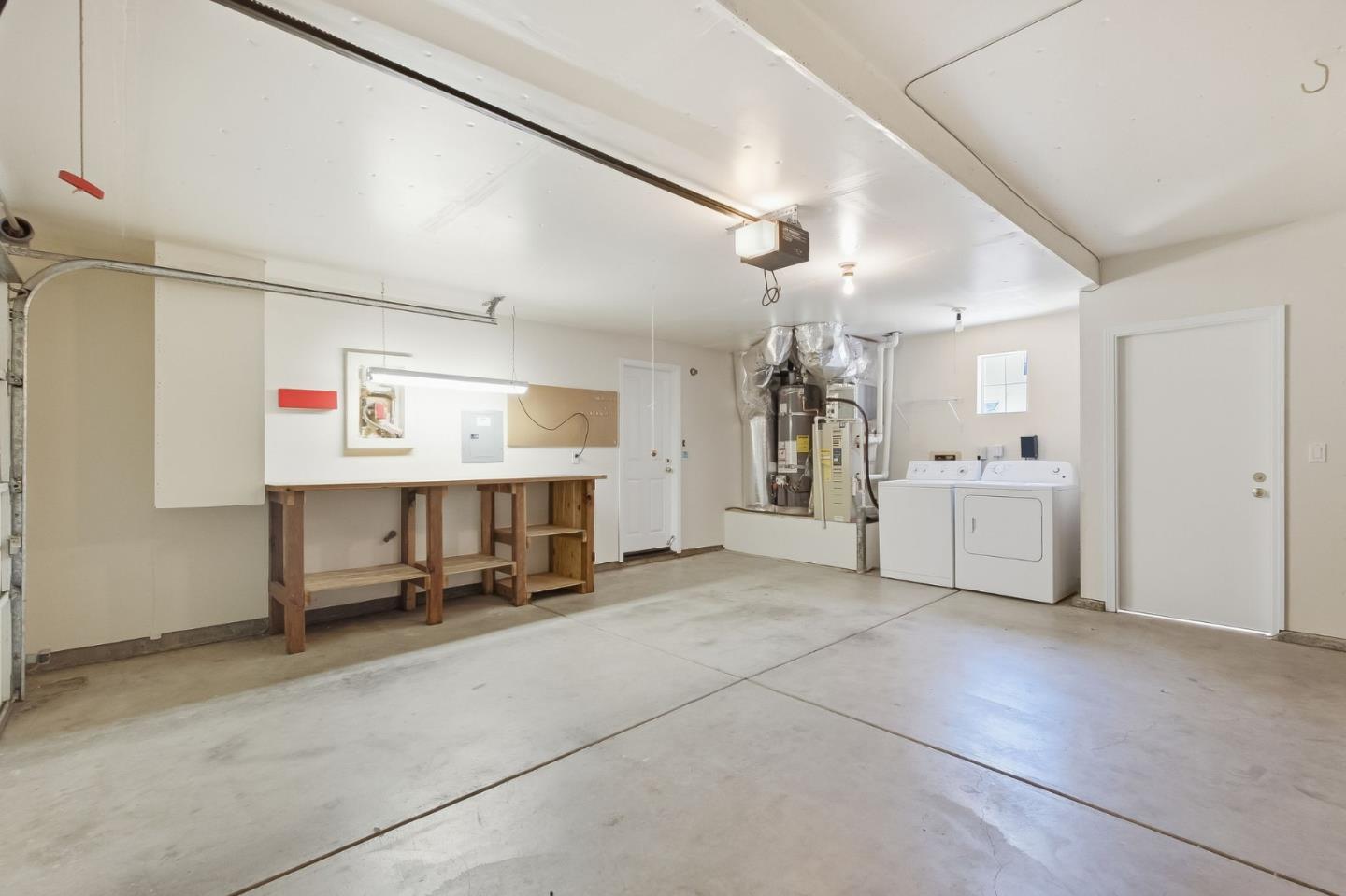 Garage with a concrete floor, wooden workbench, and washer and dryer.