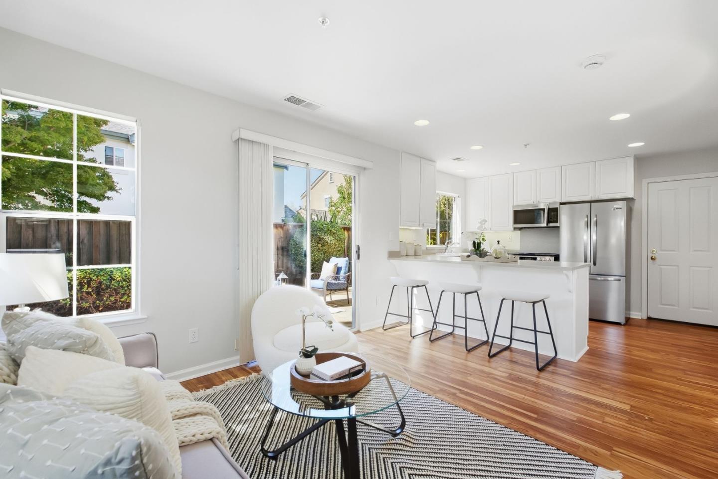 Open-plan living room and kitchen with a breakfast bar, hardwood floors, and sliding doors to a patio.
