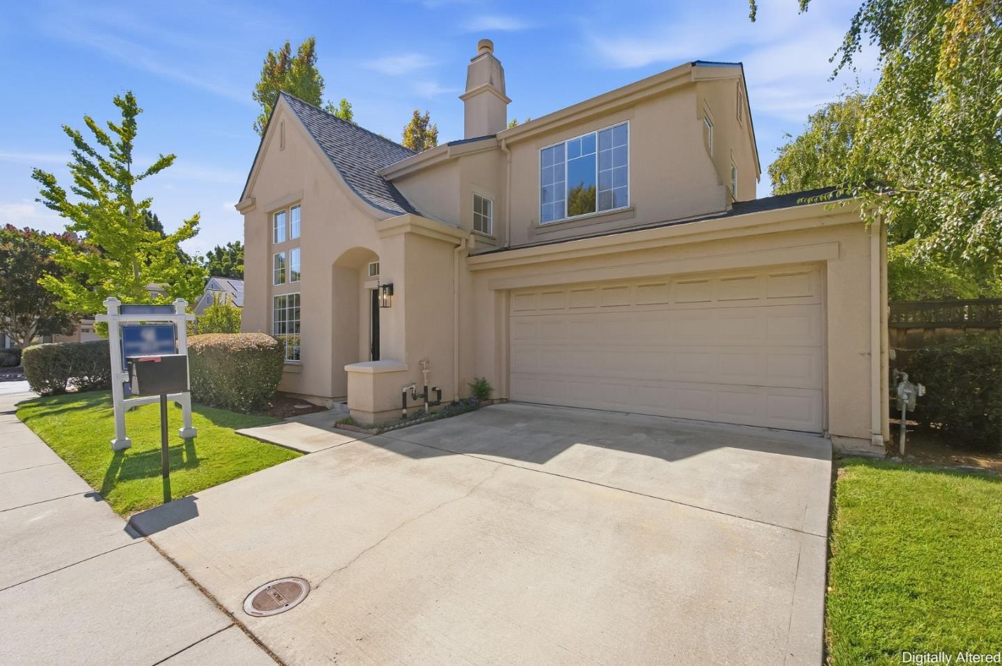Beige two-story house with a double garage, wide driveway, and front lawn.