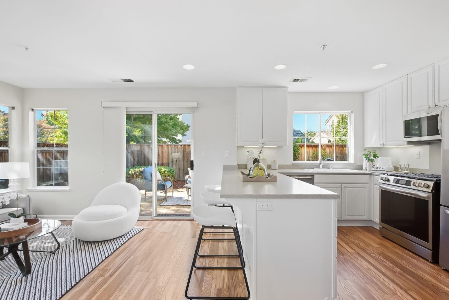 Bright open-plan kitchen with a large island, stainless appliances, and sliding doors to a patio.