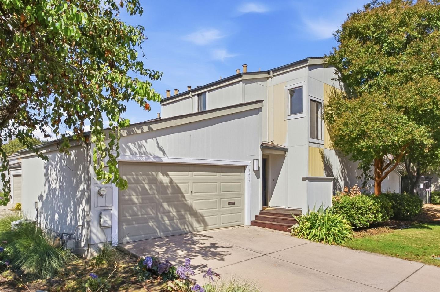 Two-story home with an attached double garage, landscaped entry, and mature trees.