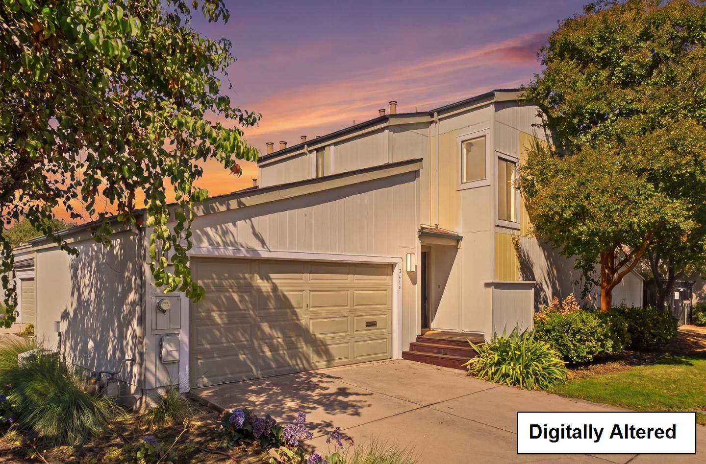 Two-story home with an attached garage and landscaped front yard at sunset.