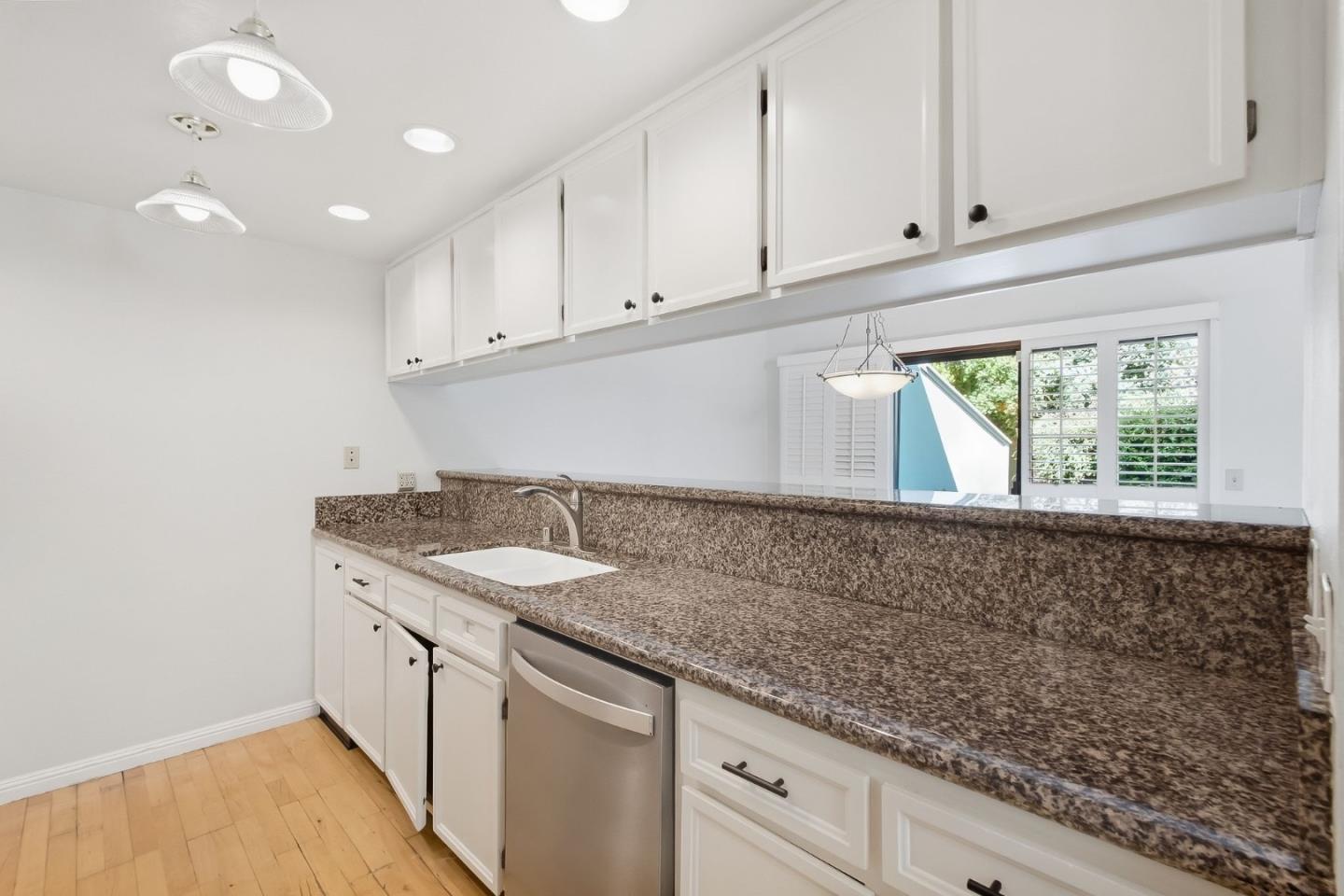Kitchen with dark granite counters, white cabinets, and a stainless steel dishwasher.